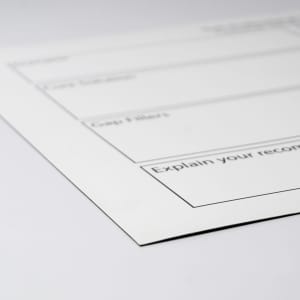 A white magnetic whiteboard with black outline sections for notes, featuring a logo in the corner.
