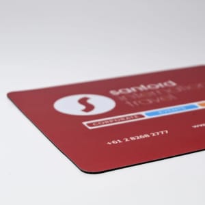 A red mouse mat with a logo and contact details in white and blue. Dimensions are 230mm x 190mm.