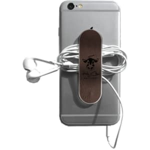 A smartphone with a brown leather strap holding wrapped earphones, featuring a logo. The phone is silver in colour.