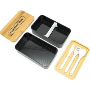 A two-layer lunch box with a bamboo lid, featuring a black inner compartment and a tray with cutlery.