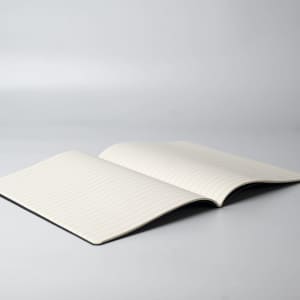 An open notebook with lined pages, featuring a plain black cover and a minimalist design.