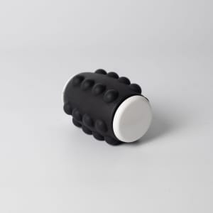A black and white Whirl Popper Spinner featuring raised bumps on its surface, designed for interactive play.