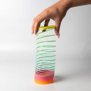 A drink bottle shaped like a spiral, featuring green, yellow, and gradient pink to orange colours. It has a logo.