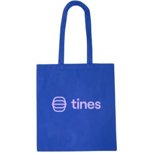 A vibrant blue cotton tote bag featuring a logo on one side. The bag has sturdy handles for easy carrying.