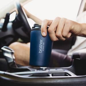 A drink bottle in dark blue, featuring a logo, held in a person's hand inside a vehicle.