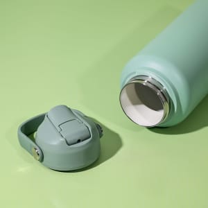 A drink bottle in a pastel green colour with a removable cap, featuring a stainless steel interior.