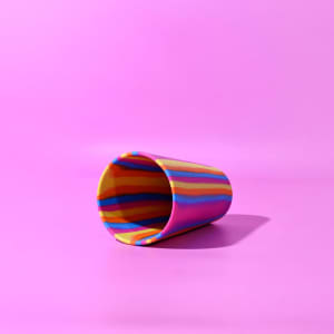A drink bottle featuring a vibrant, multi-coloured swirl design in yellow, pink, and blue, with a smooth finish.
