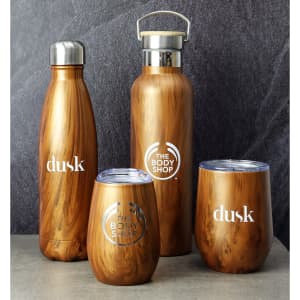 A drink bottle and three cups in a wooden finish, featuring logos, against a dark textured background.