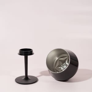 A black, detachable wine glass with a broad bowl and a separate stem. It features a logo on the base.