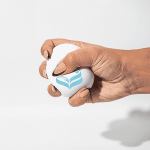 A white squeeze ball is being held, featuring a blue logo. The ball is shown being squeezed by a hand.