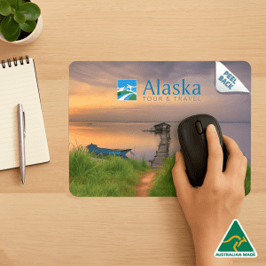 A colourful mouse mat featuring a scenic landscape with water at sunset, used with a computer mouse.