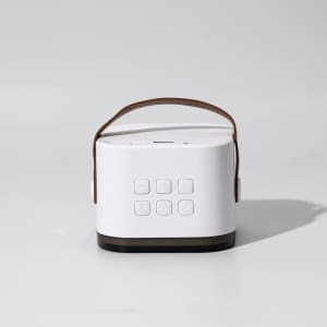 A portable karaoke machine in white and brown, featuring a handle and multiple buttons on the front.