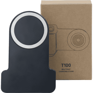 A wireless charger in black with a silver accent, positioned in front of its cardboard packaging.