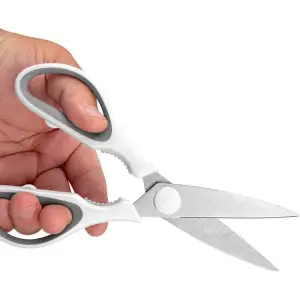Kitchen scissors with stainless steel blades and a grey and white grip, held in a hand. Features a magnetic holder.
