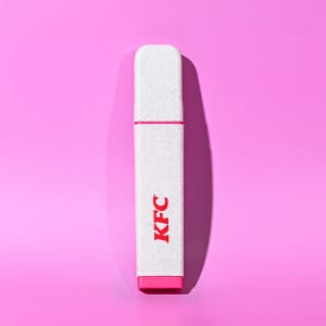 A highlighter in white with a pink cap, featuring a logo on its side, set against a pink background.