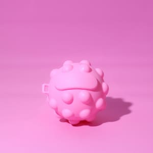 A pink, textured stress ball in a rounded shape with small protrusions, set against a pink background.