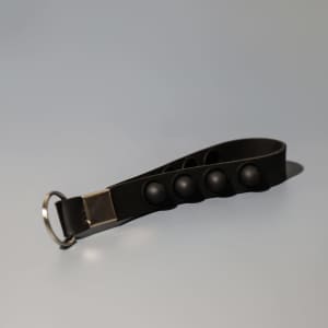 A black key chain stress reliever with popper buttons and a silver attachment ring.