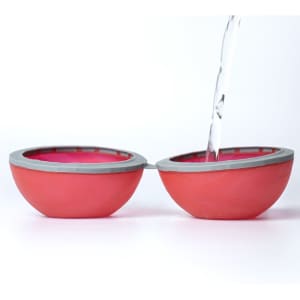 A red and grey reusable water balloon split in half, with water being poured into one half.