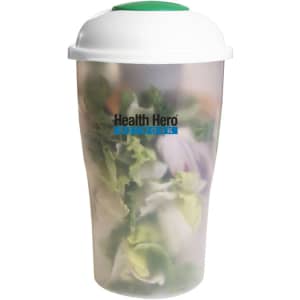A translucent salad shaker with a white lid and green top, filled with fresh salad ingredients. It features a logo.