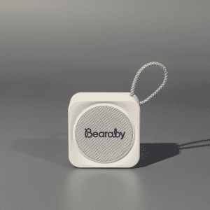 A compact white portable Bluetooth speaker with a loop for attachment. Features a logo on the front.