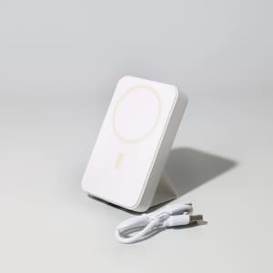A white wireless charging power bank with a stand and a USB charging cable.