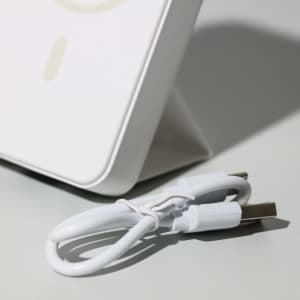 A white wireless charging power bank with a USB cable beside it, featuring a sleek, modern design.