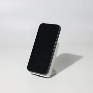 A black wireless charging power bank stands on a white base, showcasing its sleek design.