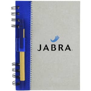A recycled journal book with a grey cover, blue spiral binding, and a pen attached. It features a logo on the front.