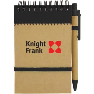 A brown recycled jotter pad with a black pen and elastic band, featuring a logo on the cover.
