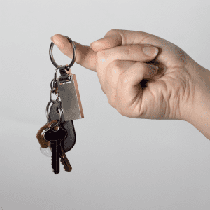 A hand holding a silver keychain with multiple keys attached, featuring a rounded key ring.