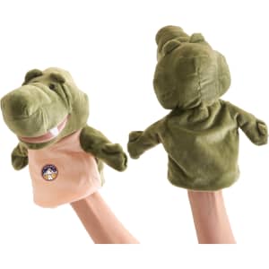 Two green crocodile hand puppets are held up, featuring plush fabric and a logo on one side.