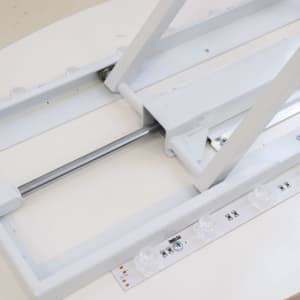 A backlit LED spring-up display oval with a white frame and base, featuring adjustable support mechanisms.