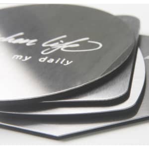 An octagonal metal coaster set featuring a shiny silver finish, stacked with a branding logo visible on top.