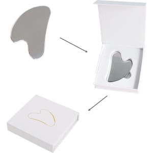 A stainless steel gua sha massage tool in a white box, featuring a sleek and reflective surface.