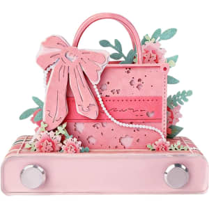 A pink 3D paper art handbag-shaped notepad adorned with floral designs and a decorative bow. It features a silver base.
