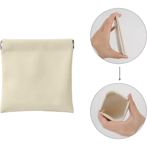 A small, cream-coloured pocket cosmetic bag with a zipper, shown from the front and being held by a hand.