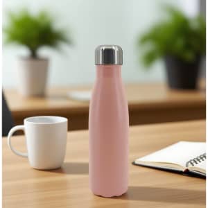 A drink bottle in pink with a stainless steel lid, set on a wooden table near a mug and a notebook.
