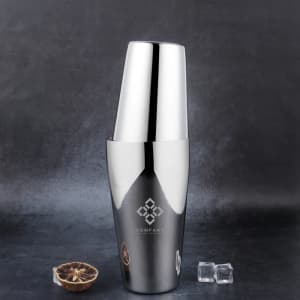 A stainless steel cocktail shaker in shiny silver, featuring two sizes, alongside ice cubes on a dark background.