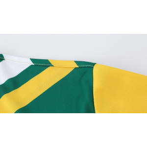 A close-up of a long-sleeved shirt featuring green and yellow polyester micro mesh with a logo.
