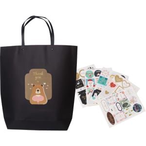 A large black boutique paper bag with handles and assorted decorative stickers displayed beside it.