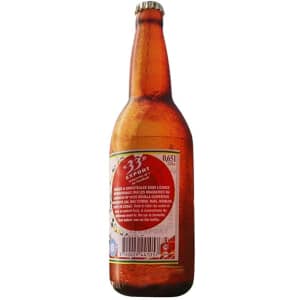 An inflatable beer bottle in amber colour with a label and a metallic cap. It features a logo on the bottle.