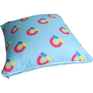 A square cushion featuring a light blue background with colourful magnet patterns. It has a zip closure and a logo.