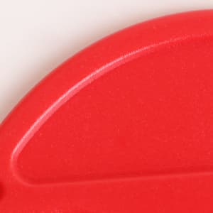 A red coloured letter opener with a smooth, curved edge and a small branding logo.
