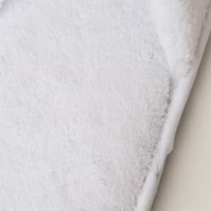 A pair of soft white hotel slippers featuring a plush texture and a branded logo on the side.