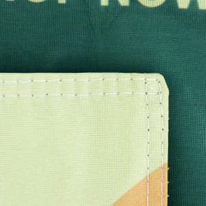 A green garden flag featuring a stitched corner detail in light green fabric. It has a logo or branding element.