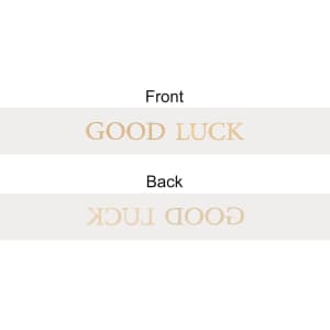 A soft ribbon in a light colour featuring the words "GOOD LUCK" printed on both sides. It has a simple branding logo.