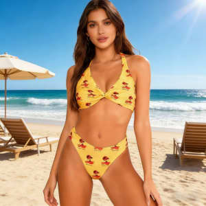 A yellow bikini top with a twist design, featuring a pattern, set against a beach backdrop with loungers and umbrellas.