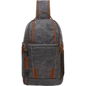 A grey waxed canvas camera sling bag with brown leather accents and adjustable straps. Features side pockets and a logo.