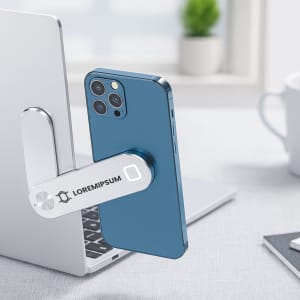 A silver laptop extension arm holds a blue smartphone, positioned beside a blurred workspace with a coffee cup.