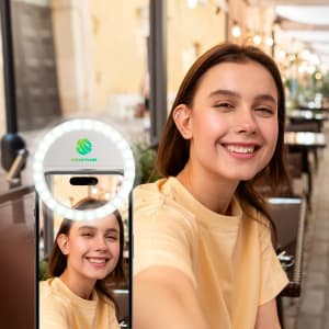 A phone displaying a ring selfie light, featuring a smiling woman in a light-coloured top and a café setting.